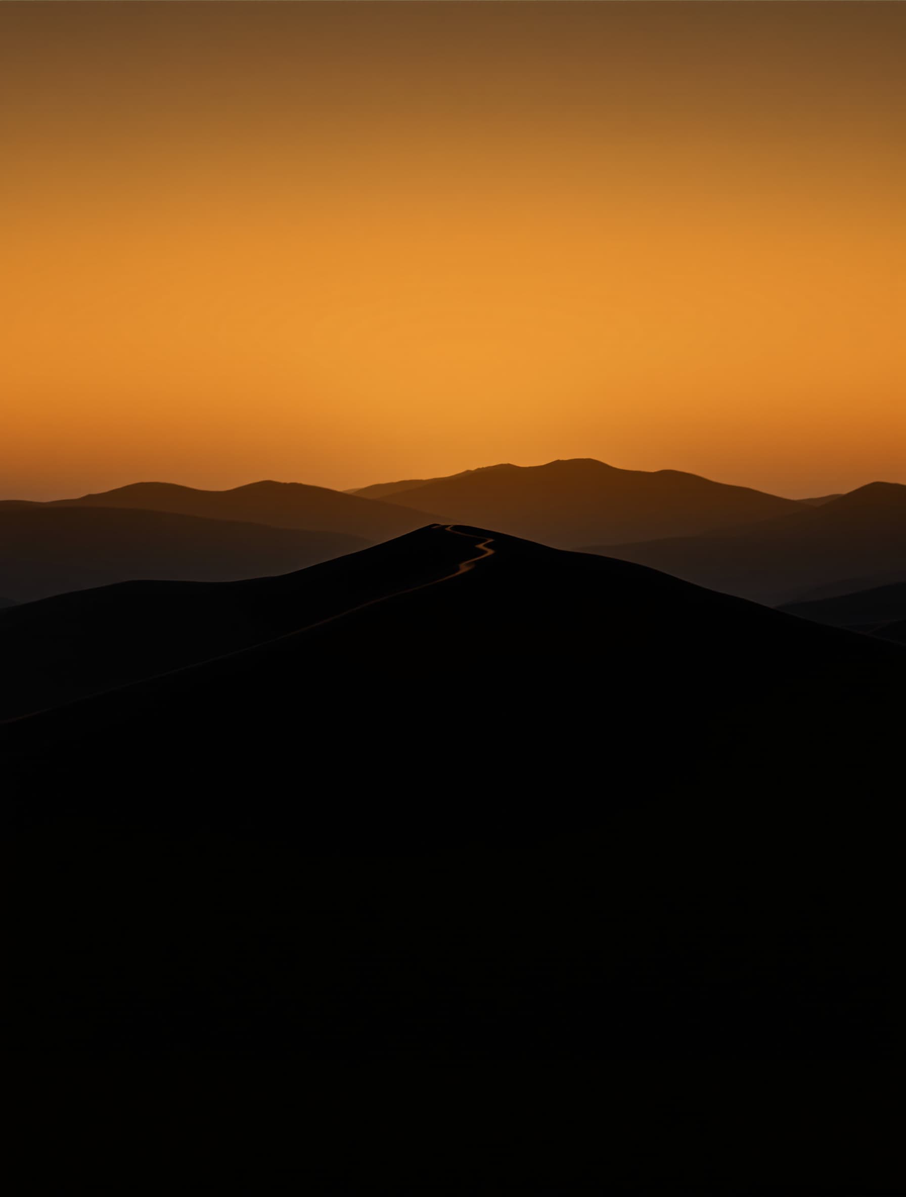 An AI-generated landscape photograph of a ridgeline at last light, warm rim against deep valley shadow